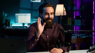 Content creator adjusting professional microphone in studio before starting vlog, recording with selfie camera. Man in neon lit home studio