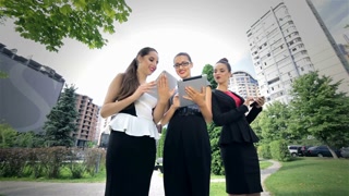 Three successful business woman working on the tablet, discuss news and delight