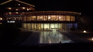 Night view of the outdoors pool in a luxury hotel in Alps. People swimming outside in Alps. Luxury life. 